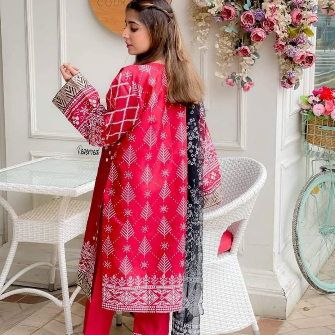 Woman in a red and white patterned outfit standing in a decorated room with flowers and a bicycle.