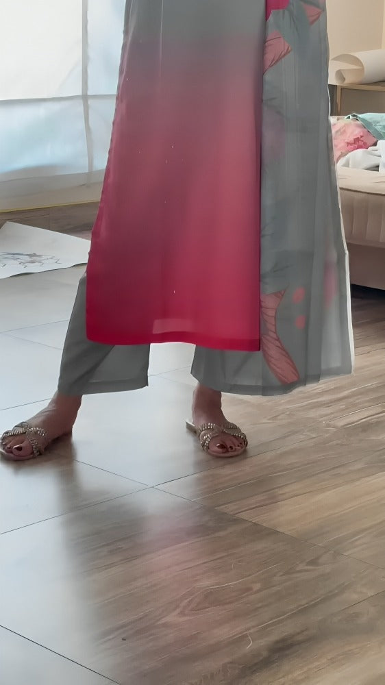 Person wearing a long, light-colored dress with a red section on a wooden floor.