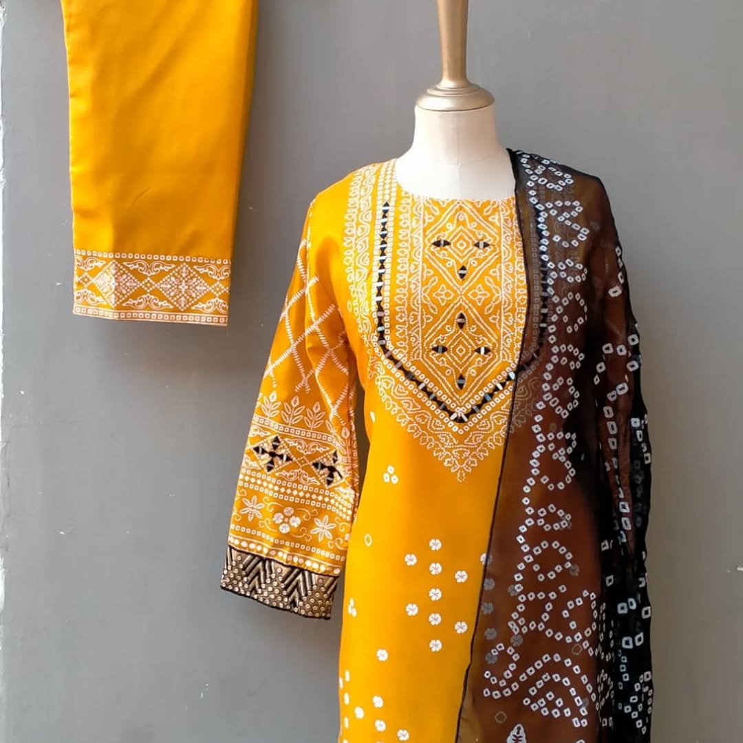 Yellow embroidered outfit with a black and white patterned dupatta on a mannequin against a gray background.